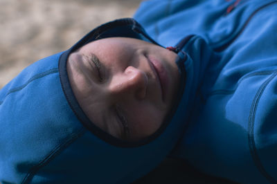 Portrait of a sleeping tourist woman in a hood-clothing on the beach. close-up