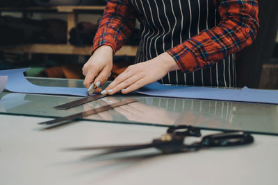 Sewing process. small business making leather and canvas bags. woman hands cutting leather with