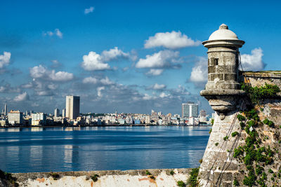 City at waterfront against cloudy sky