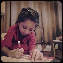 Portrait of teenage girl holding table at home