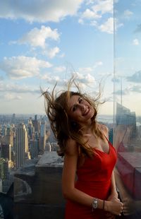 Beautiful young woman in city against sky