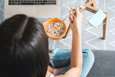 Midsection of woman using phone while sitting on table