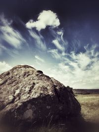 Rocks on landscape against cloudy sky