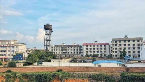 Buildings by water tower against sky in city