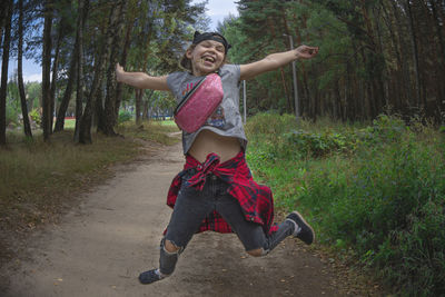 Full length of happy young woman in forest
