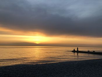 Silhouette person on beach against sky during sunset