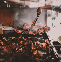 Midsection of person preparing food on barbecue grill