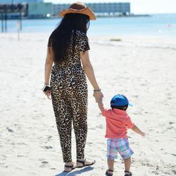 Rear view of woman with son walking at beach