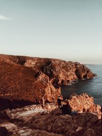 Rocks by sea against clear sky