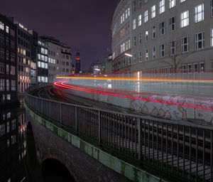 Light trails on street against buildings at night