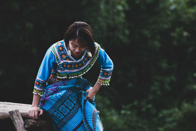 Young woman smiling against blurred trees