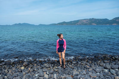 Young woman looking away while standing at beach