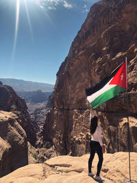 Woman holding jordanian flag on the top of the mountain in petra 