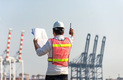 Rear view of man standing at construction site against sky