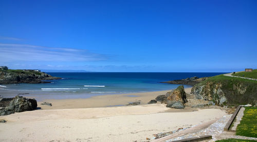 Scenic view of beach against clear blue sky