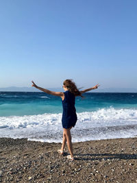 Full length of woman standing on beach against clear sky