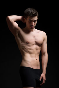 Midsection of shirtless man against black background