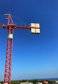 Low angle view of crane against clear blue sky