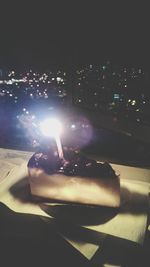 Man sitting on table in illuminated city at night