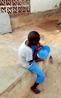 Side view of boy sitting on wall