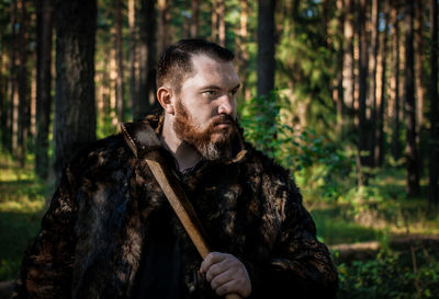 Angry man holding axe against trees in forest