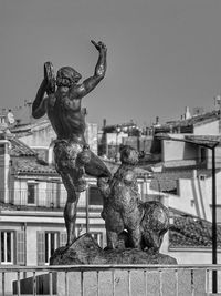 Statue in city against sky