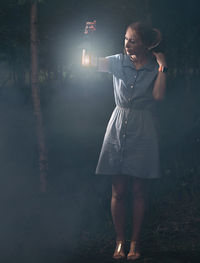 Full length of woman holding lit lantern at night