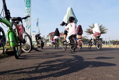 People riding bicycle on road against sky