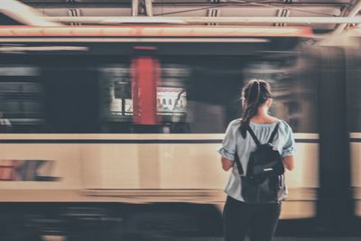 Rear view of woman standing by train at railroad station