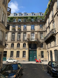 Cars on road by buildings in city against sky