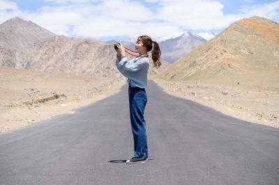 Full length of woman standing on mountain road