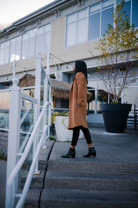 Full length side view of woman walking on footpath against building