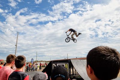 Rear view of people riding motorcycle against sky