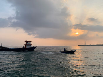 Boat sailing in sea against sky during sunset