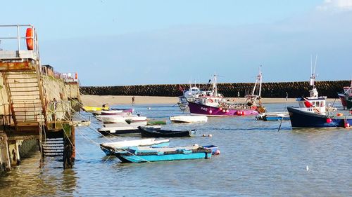 Boats moored at harbor against sky