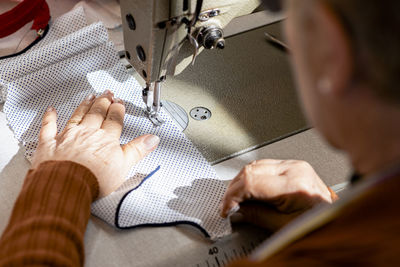 Close up of senior dressmaker hands using a sewing machine.