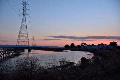 Silhouette bridge over river against sky at sunset