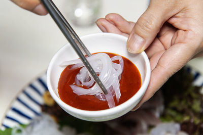 Cropped hand of woman holding squid sashimi 