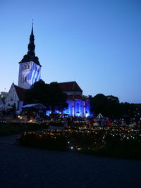 Illuminated buildings against blue sky at night