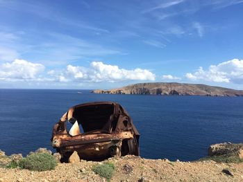 Abandoned car on shore against sky