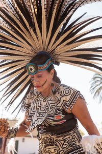 Low angle view of woman holding palm tree