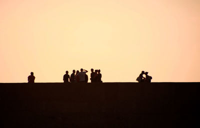 Silhouette people standing against clear sky during sunset