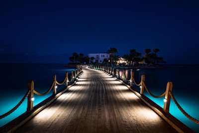 Pier over sea against sky at night