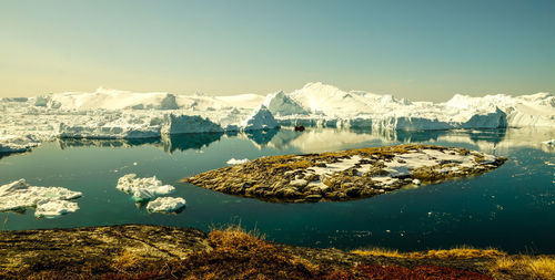 Scenic view of lake by snowcapped mountains against clear sky