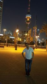 Rear view of man standing on illuminated street at night