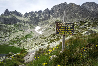 View of information sign on landscape against mountains