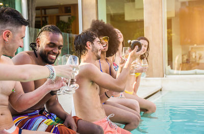 Friends enjoying drinks while sitting at poolside