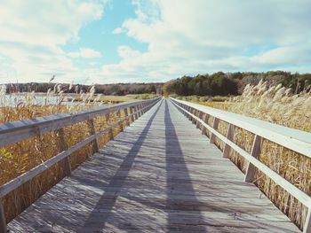 Footbridge over salt marsh  against sky