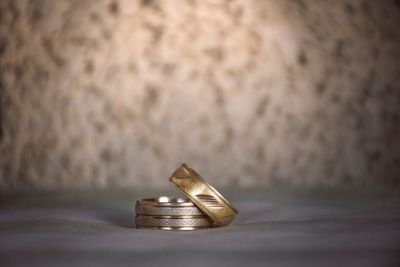 Close-up of wedding rings on table against wall