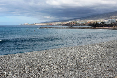 Stony beach at playa de las americas on canary island tenerife with blue water and blue sky